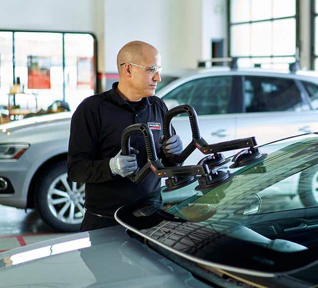 A Speedy Glass employee replaces a windshield