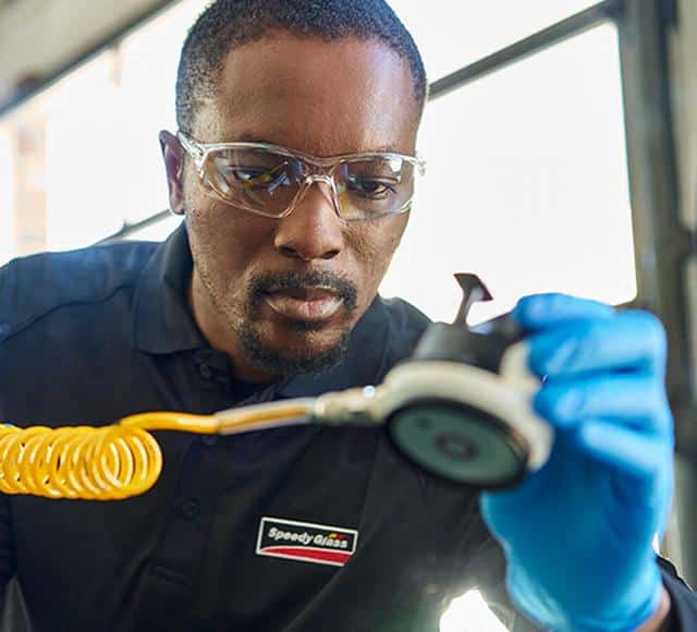 A Speedy glass employee repairs a windshield